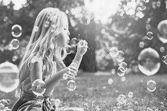 Mädchen bläst Seifenblasen auf einer Blumenwiese